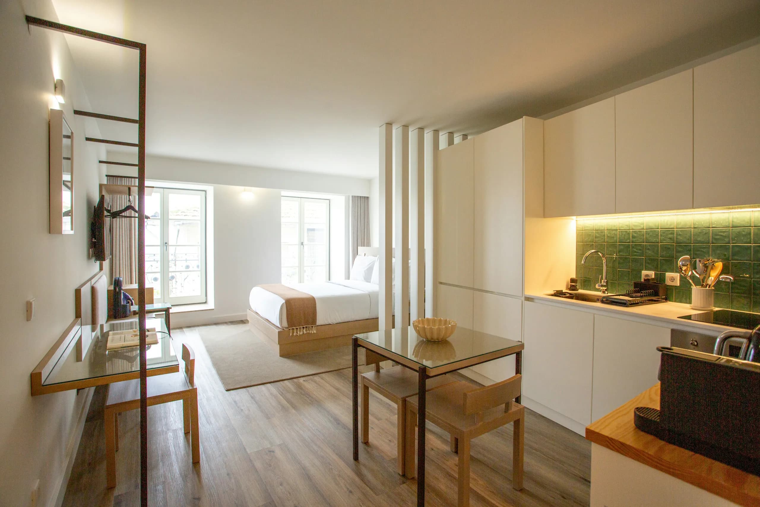 Studio-Apartment mit Bett, Essplatz und Küchenzeile mit grünen Fliesen