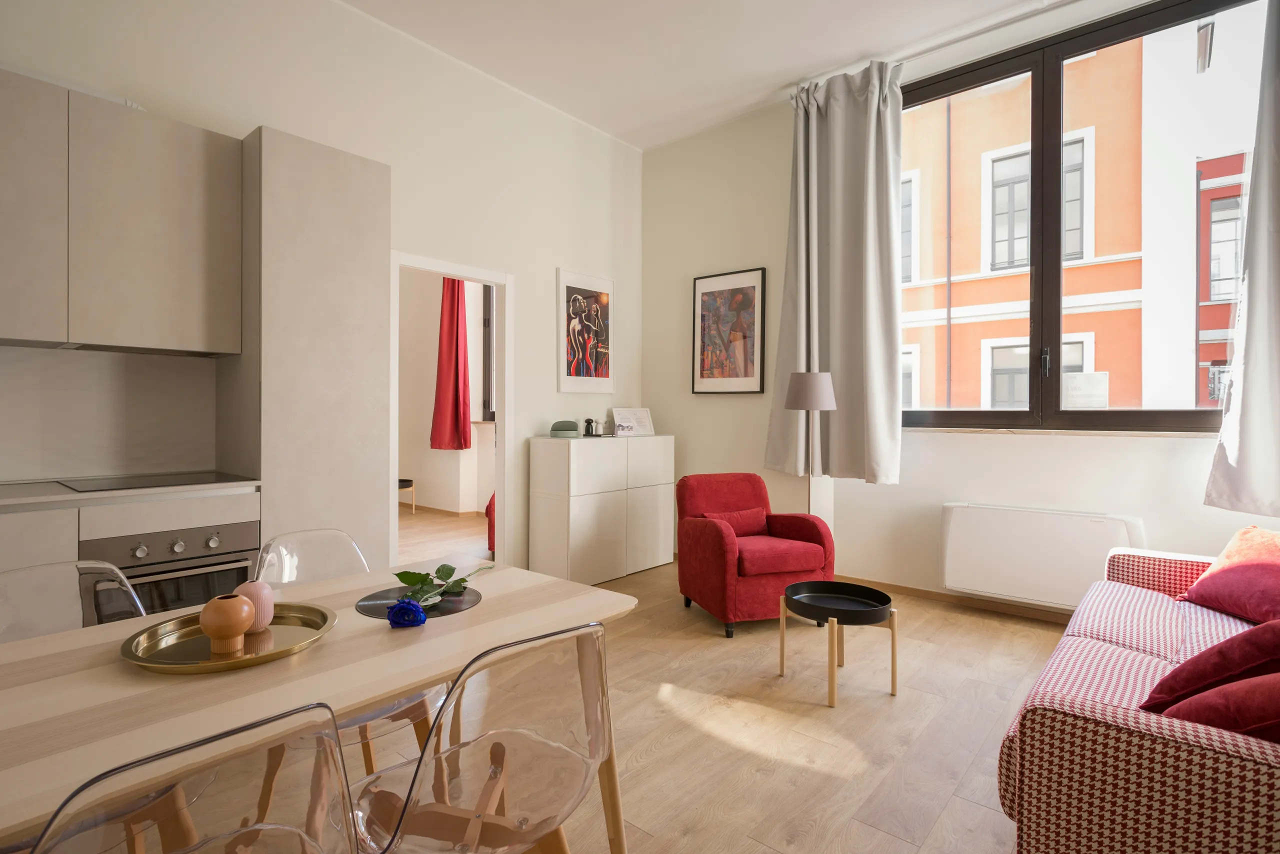 Wohnküche mit Essplatz, rotem Sessel und Blick zur Nachbarfassade