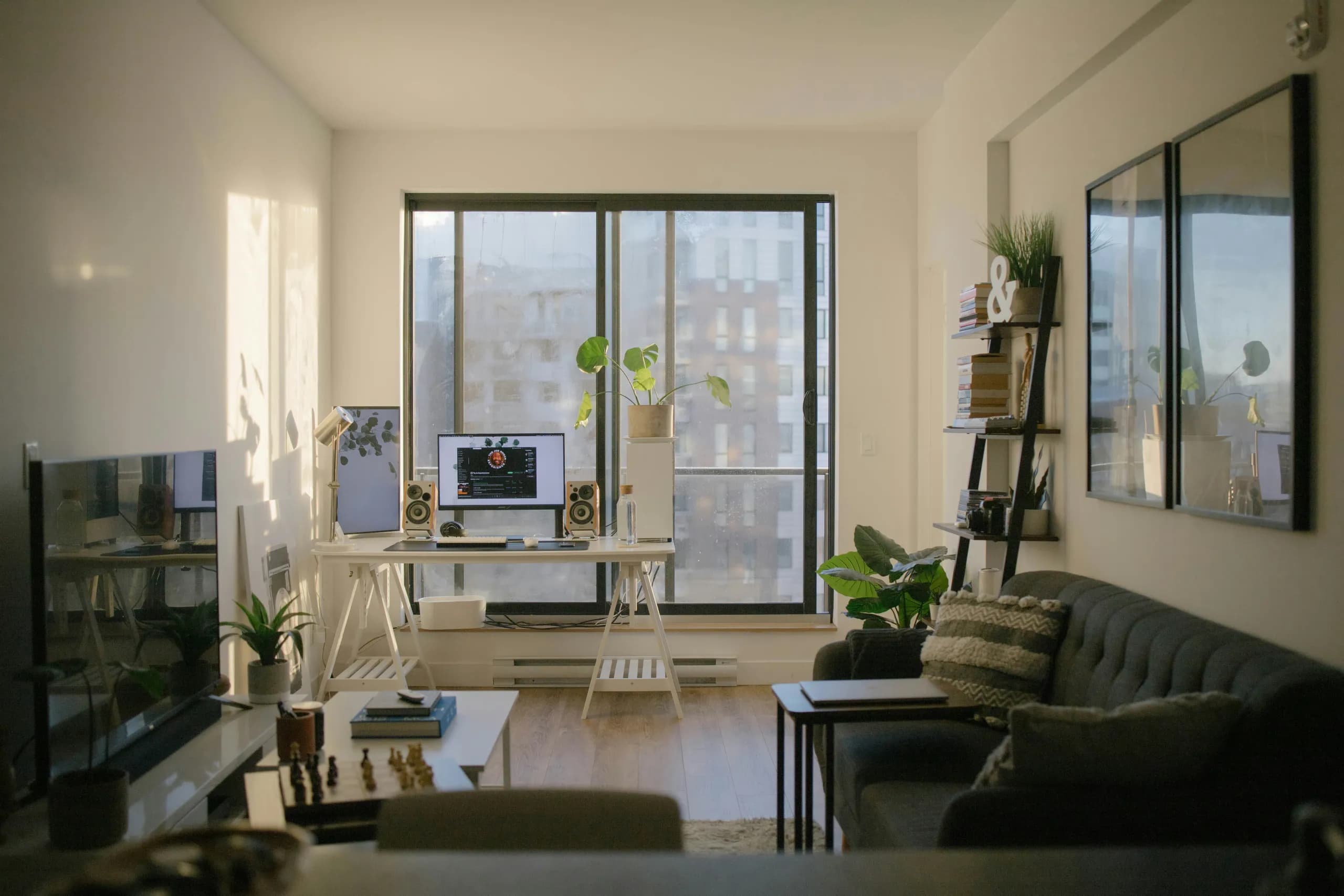 Wohnraum mit Schreibtisch vor der Balkontür und grauem Sofa