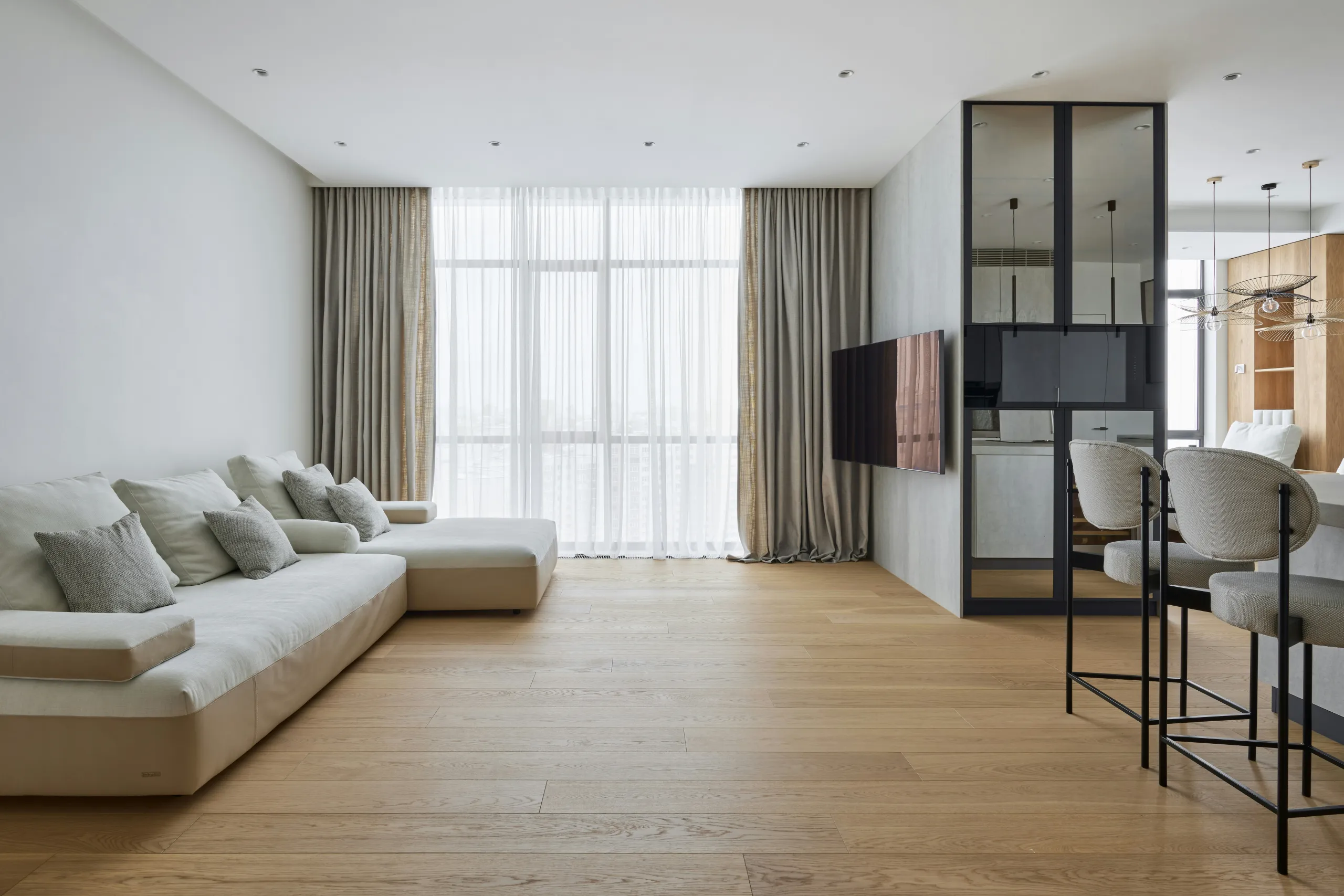 Minimalistisches Wohnzimmer mit hellem Ecksofa und bodentiefen Vorhängen