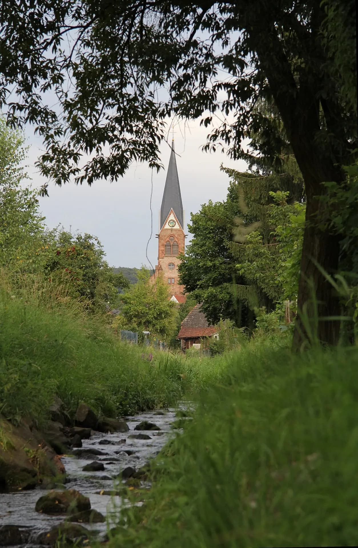 Bachlauf mit Blick auf den Kirchturm in Aschaffenburg-Schweinheim