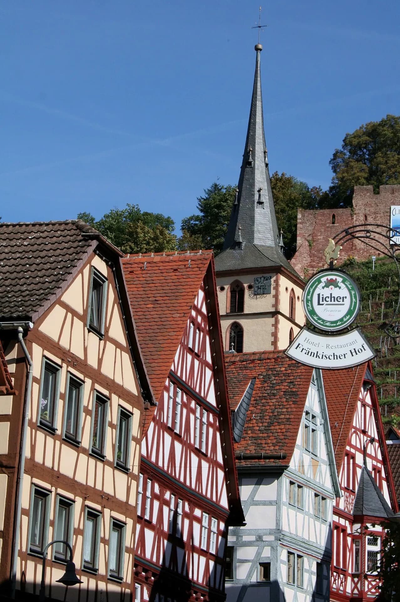 Fachwerkzeile mit Kirchturm und Burgruine im Hintergrund in Klingenberg am Main