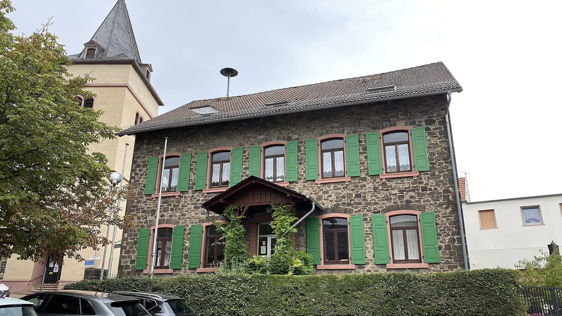 Bruchsteinhaus mit grünen Fensterläden am Pfarrhof in Maintal-Hochstadt