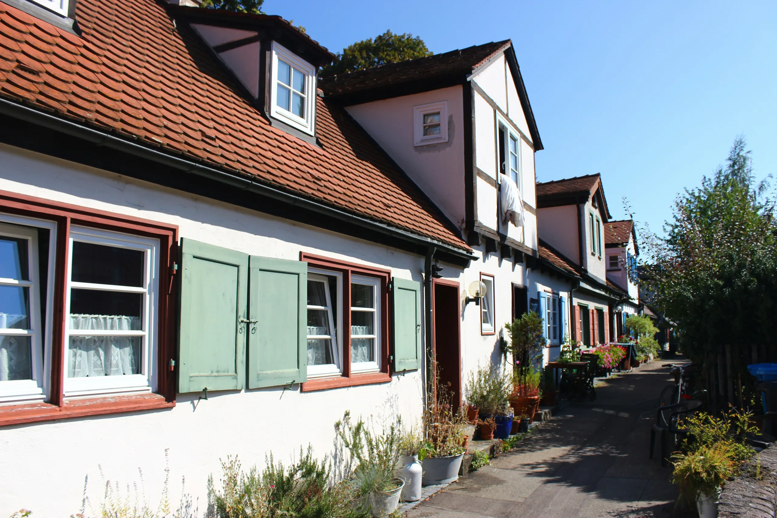 Sanierte Altstadthäuser mit roten Dachschindeln und Fensterläden