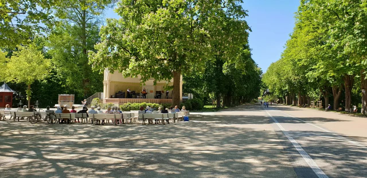 Pavillon mit Café-Terrasse unter alten Bäumen im Kurpark von Bad Homburg