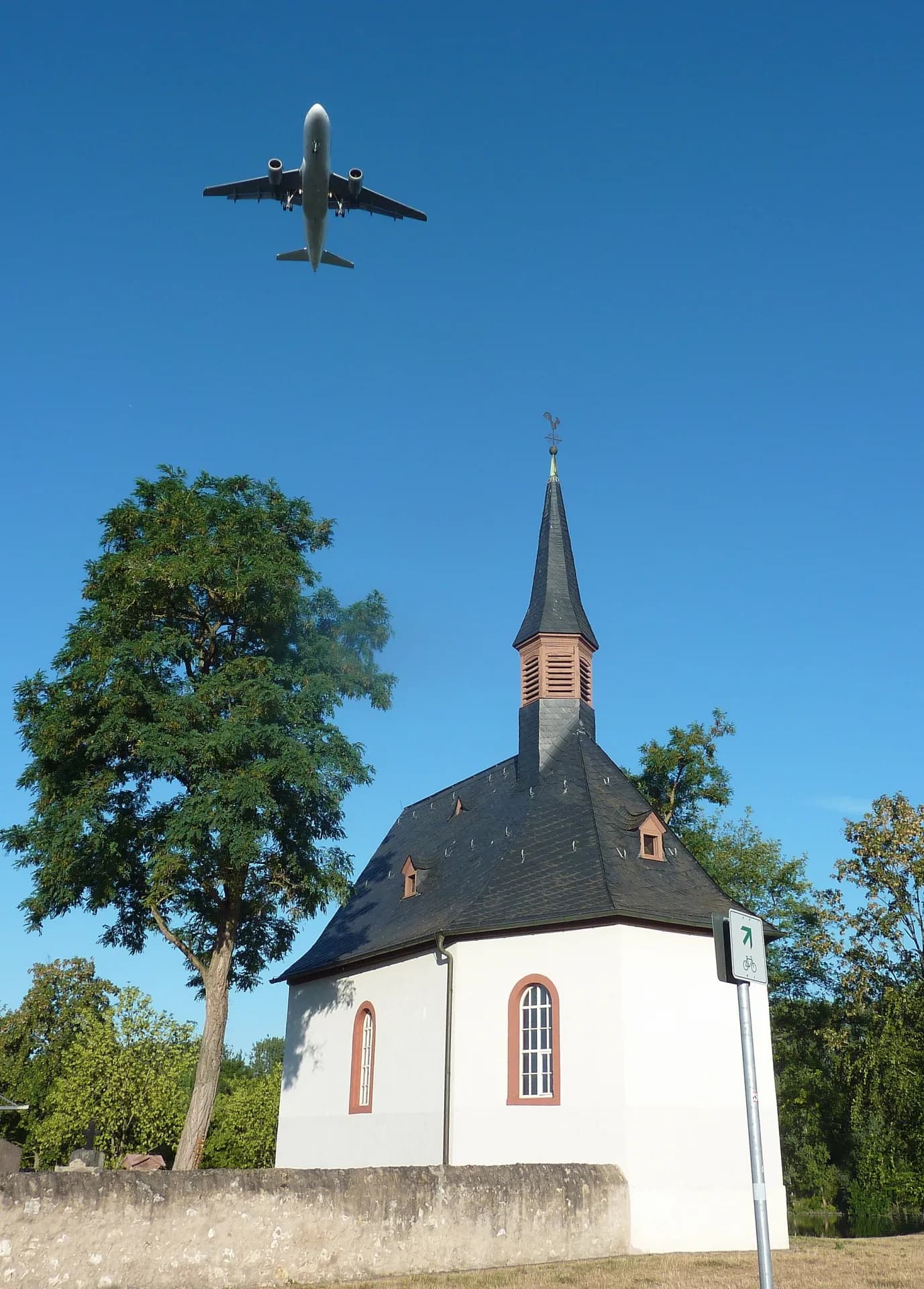 Mönchhofkapelle mit überfliegendem Flugzeug in Raunheim