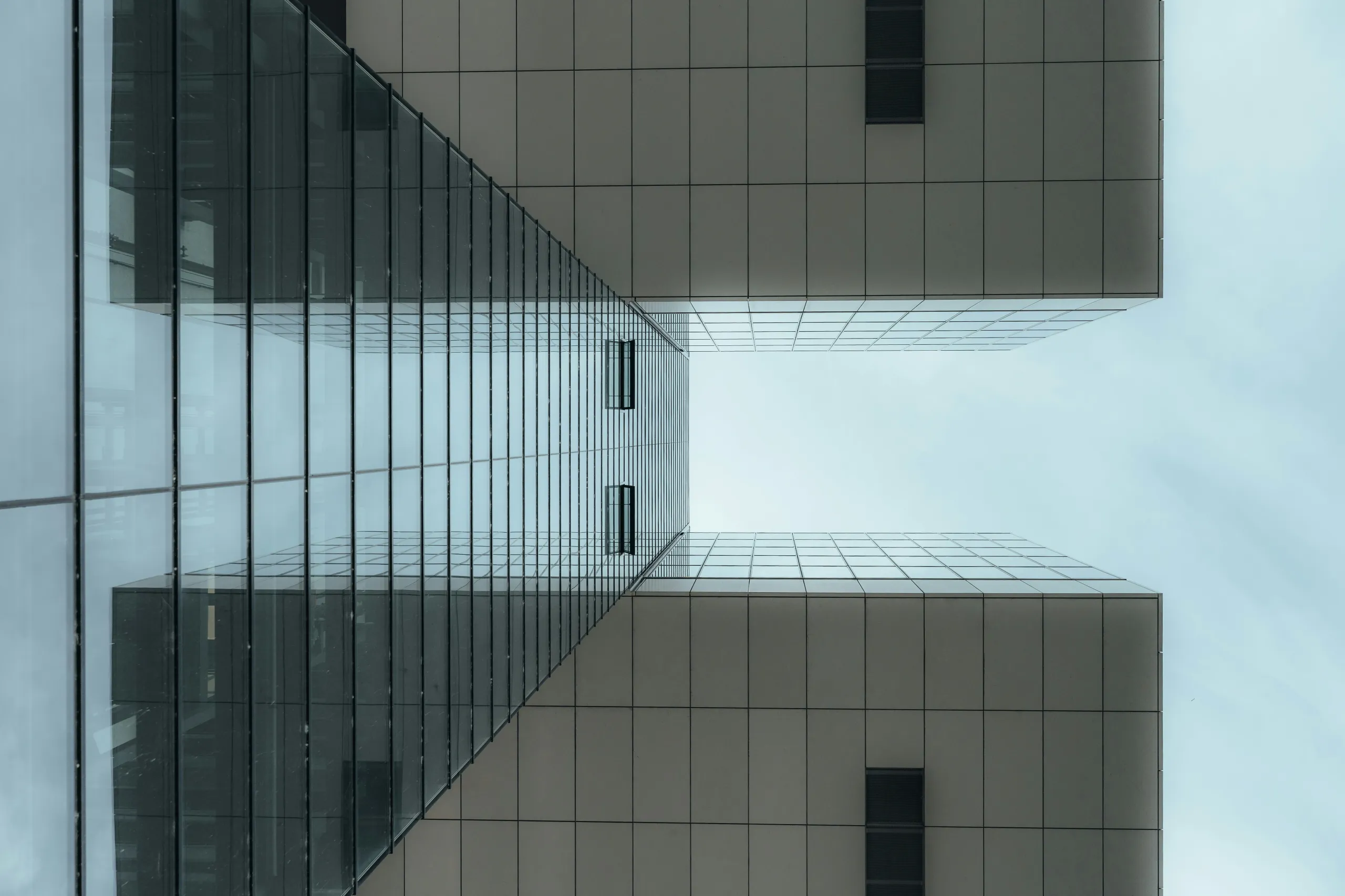 Blick nach oben zwischen Glas- und Steinfassaden eines Büroensembles
