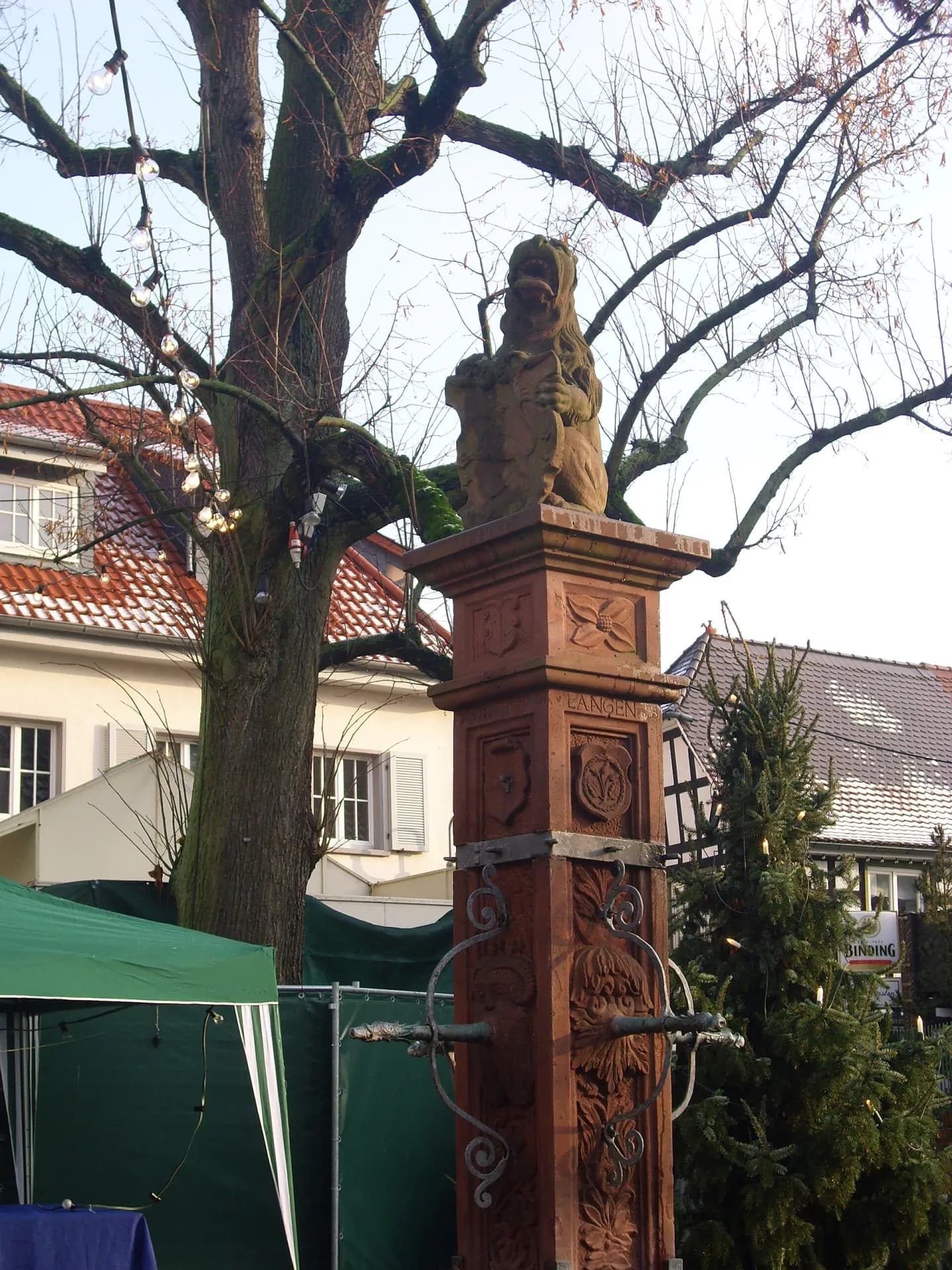 Vierröhrenbrunnen in Langen vor Baumkulisse