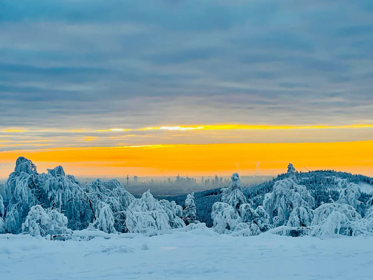 Verschneiter Taunus mit Blick auf die Frankfurter Skyline bei Sonnenuntergang